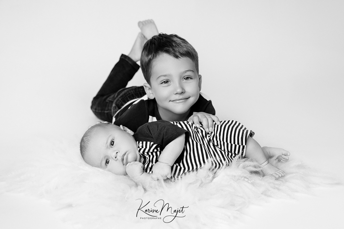 photographe naissance issy-les-moulineaux bébé et son grand frère sur fourure blanche Karine Majet