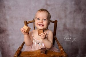shooting photo bébé Rambouillet fille dans une chaise haute en bois jouant avec des cubes karine majet