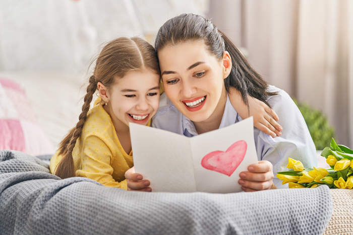 maman et sa fille lisent une carte avec un cœur offerte pour la fête des mères