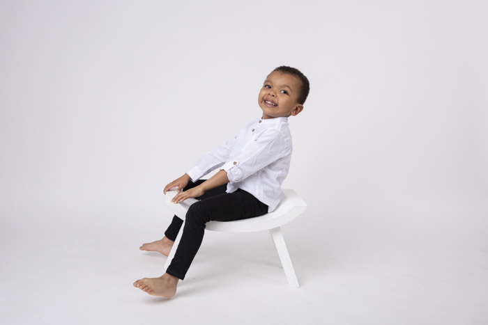 photographe enfant en studio garçon assis sur un banc blanc et s'amusant Karine Majet