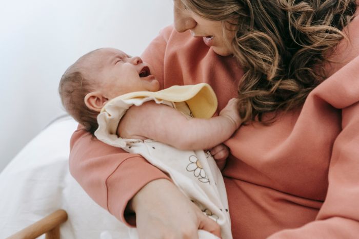 un bébé pleure dans les bras de sa maman