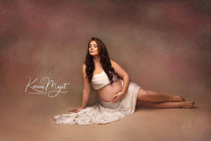 photo de grossesse artistique maman avec un voile blanc sur un fond rose karine majet