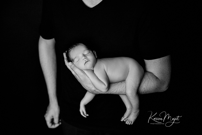 petit bébé endormi dans les bras de son père Karine Majet photographe