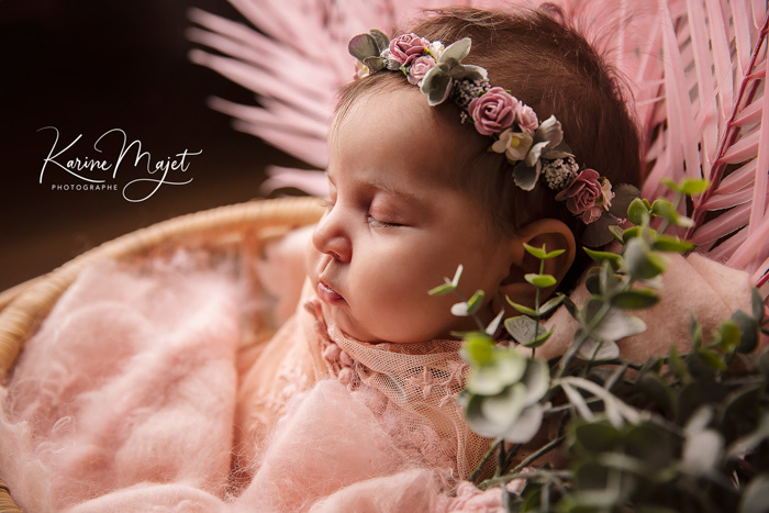 portrait d'une petite fille dans un panier avec des fleurs et une couverture rose karine majet