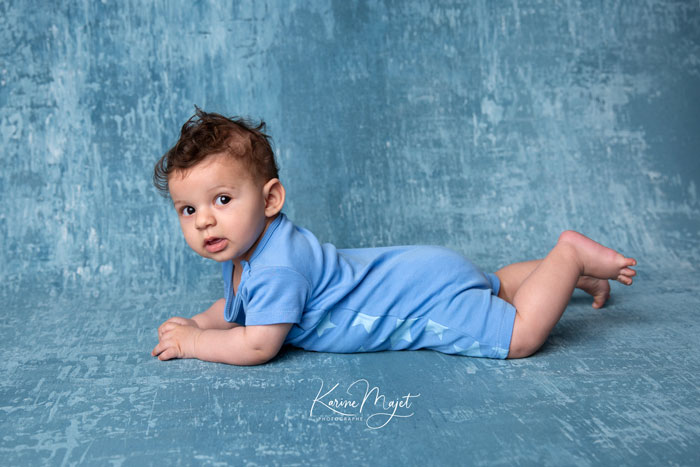garçon de quatre mois allongé sur le ventre avec un body bleu