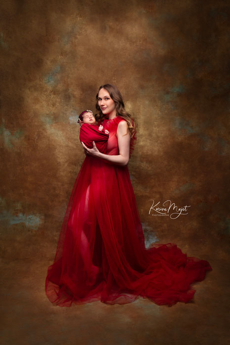 maman portant une magnifique robe rouge bordeaux en tulle et son bébé dans les bras