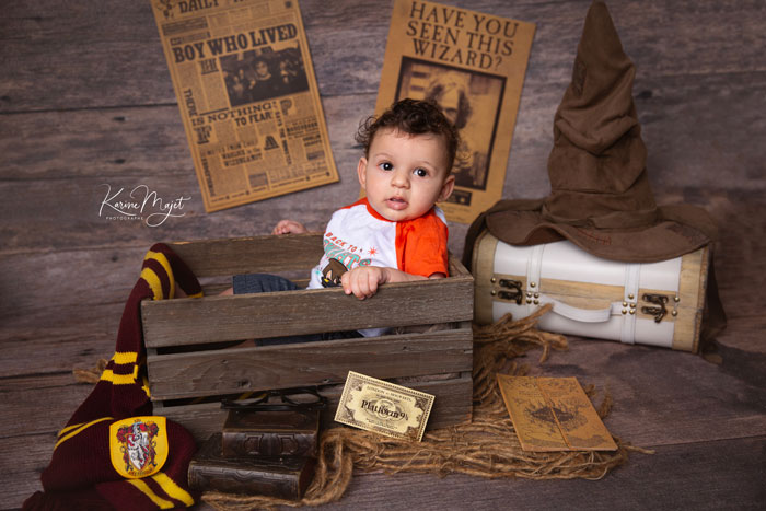 mise en scène spéciale Harry Potter, un petit garçon se tient dans une caisse en bois à côté du Choixpeau magique