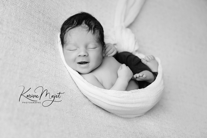 photographe naissance à Antony petit garçon qui sourit dans un cocon blanc Karine Majet