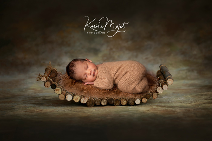 petit bébé dans un panier en rondin de bois Karine Majet