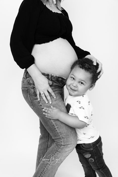 petit garçon de deux ans faisant un câlin au ventre de sa maman qui attend son deuxième bébé