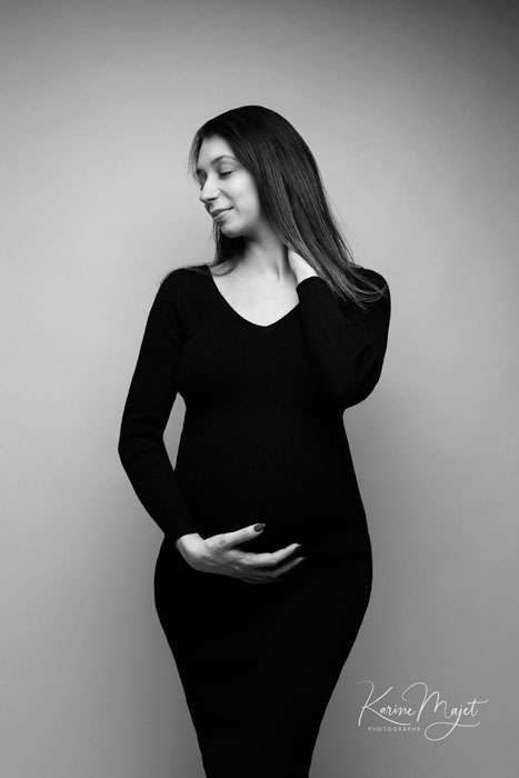 shooting mode spécial grossesse, maman avec une robe noire moulante regardant sur le côté karine majet