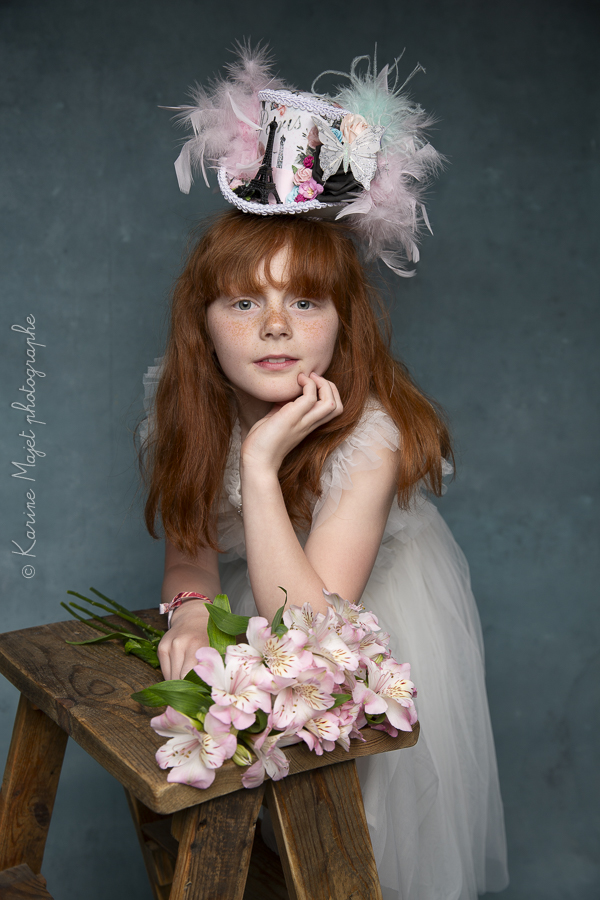 shooting d'une adolescente avec un effet artistique stylé, comme un tableau, avec un chapeau à plumes et des fleurs