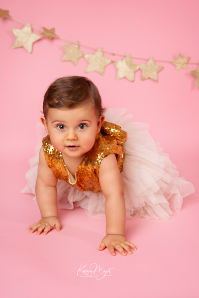 bébé fille avec une belle robe de fête dorée sur fond rose