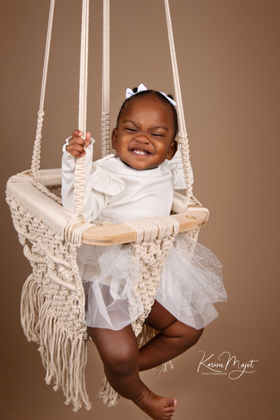 petite fille fait un grand sourire sur une balançoire