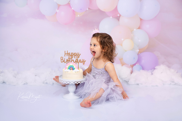 petite fille qui tire la langue devant son gâteau d'anniversaire