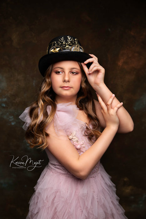 fille de 12 ans avec un chapeau noir steampunk et une belle robe mauve