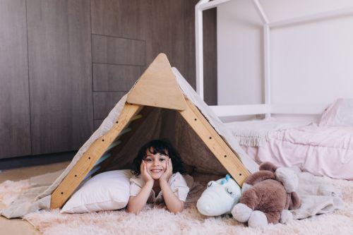 petite fille avec ses doudous sous une tente dans sa chambre