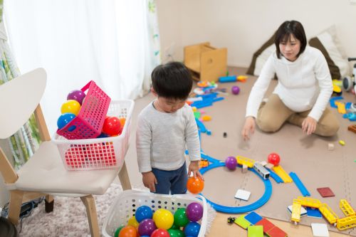 maman qui aide son fils à ranger sa chambre avec des bacs