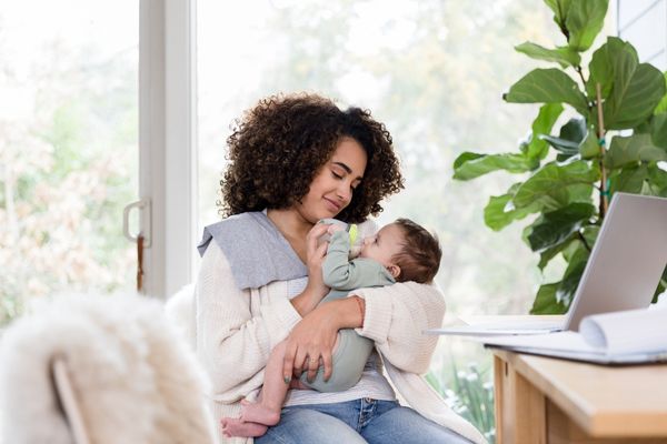 une maman donne le biberon à son fils, assise dans un canapé