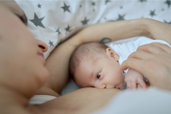 maman allongée qui allaite son enfant dans le lit