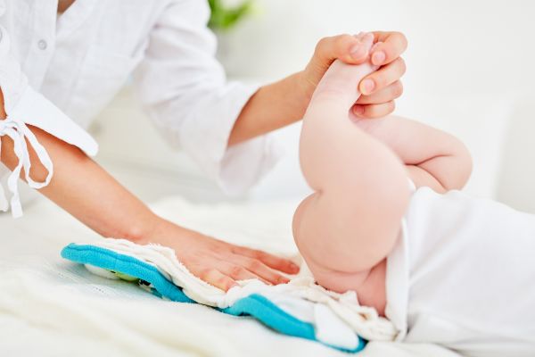 une maman change la couche lavable de son bébé