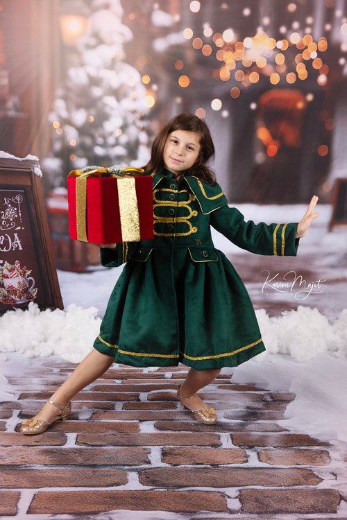 petite fille avant un manteau vert et doré pour un shooting de Noël