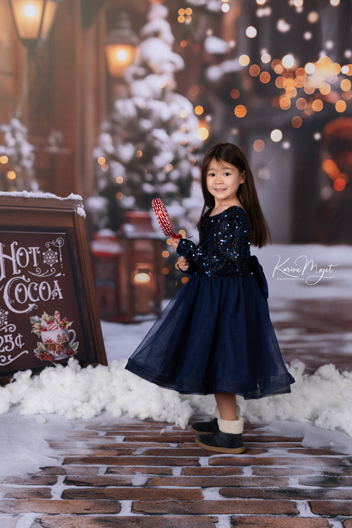 une petite fille en robe bleue marine dans un décor de Noël magnifique